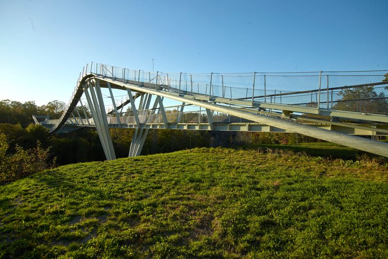 The CONSOL Energy Wingtip Bridge, a curving steel footbridge over a wooded ravine at the Summit Bechtel Reserve